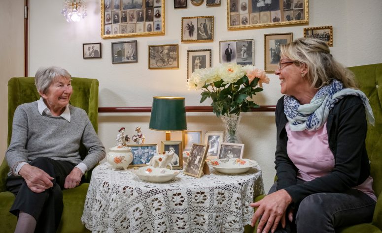 Eine Dame unterhält sich mit ihrer Pflegerin beim Kaffee trinken
