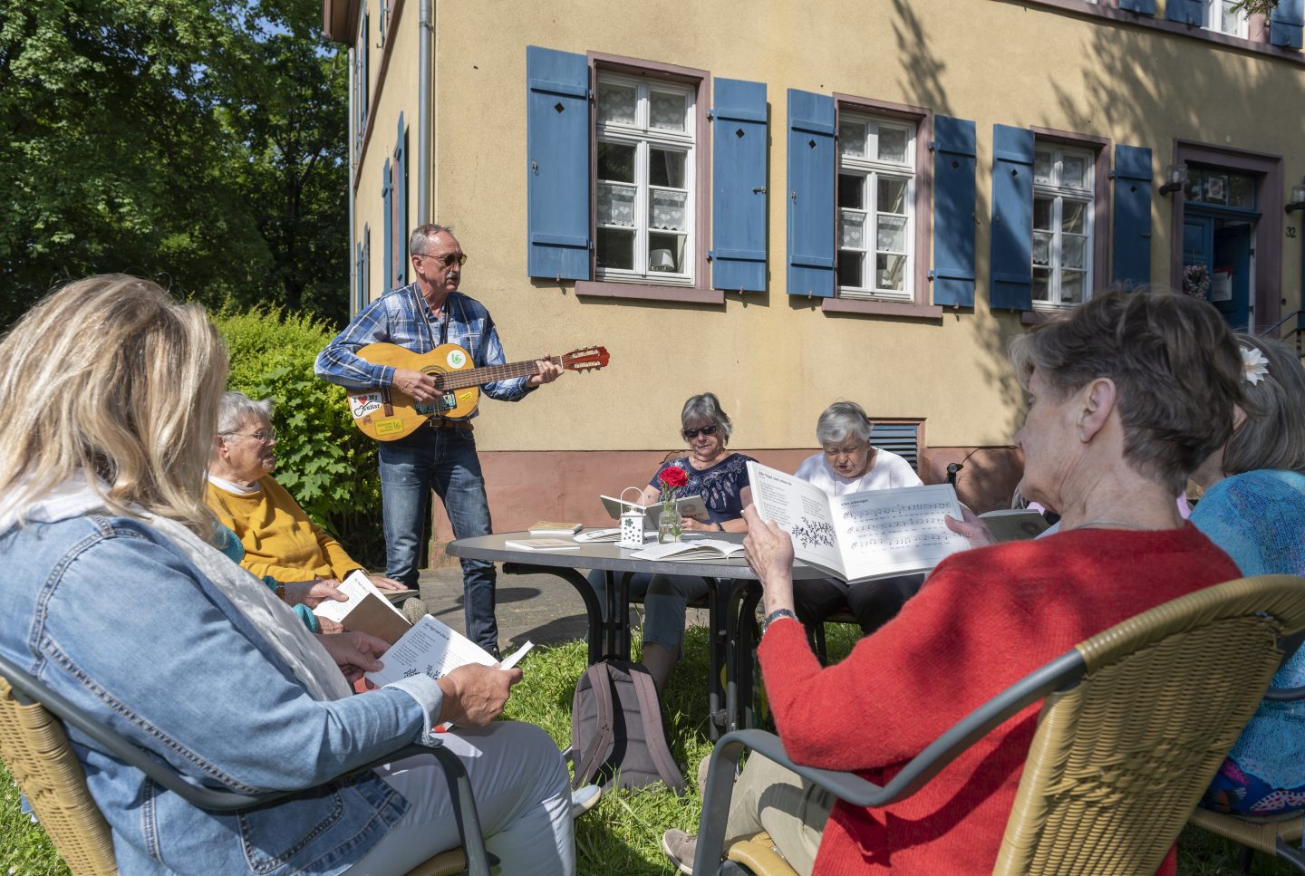 Damen und Herren treffen sich imGarten zum Musizieren